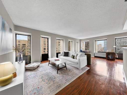 A living room with a white couch and a rug.