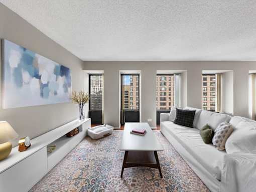 A living room with a white couch, a coffee table, and a large painting on the wall.