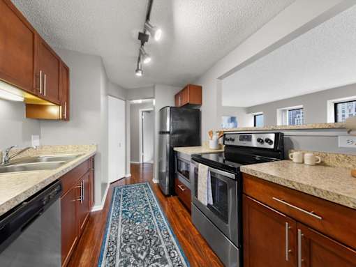A kitchen with a black refrigerator and stove top oven.