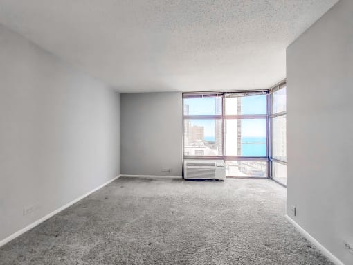 an empty room with a large window and an air conditioner