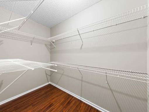 A room with a white ceiling and a wooden floor with empty shelves.