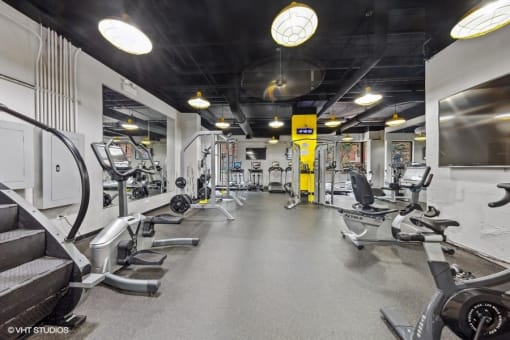 a gym with weights and cardio equipment on the floor and a wall mounted tv