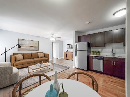 a living room with a white table and chairs and a kitchen with a stainless steel refrigerator and