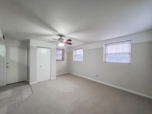 a bedroom with white walls and a ceiling fan