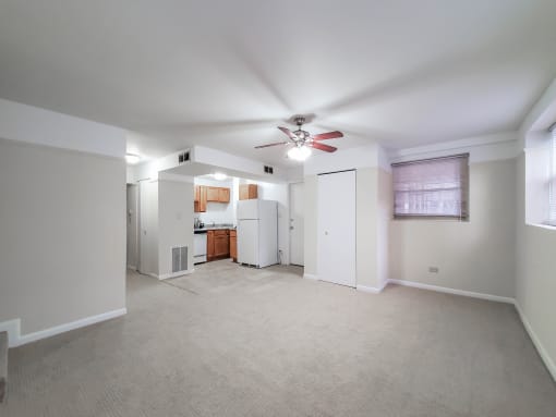 a bedroom with a ceiling fan and a kitchen in the background