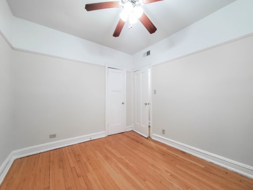 a bedroom with hardwood floors and a ceiling fan