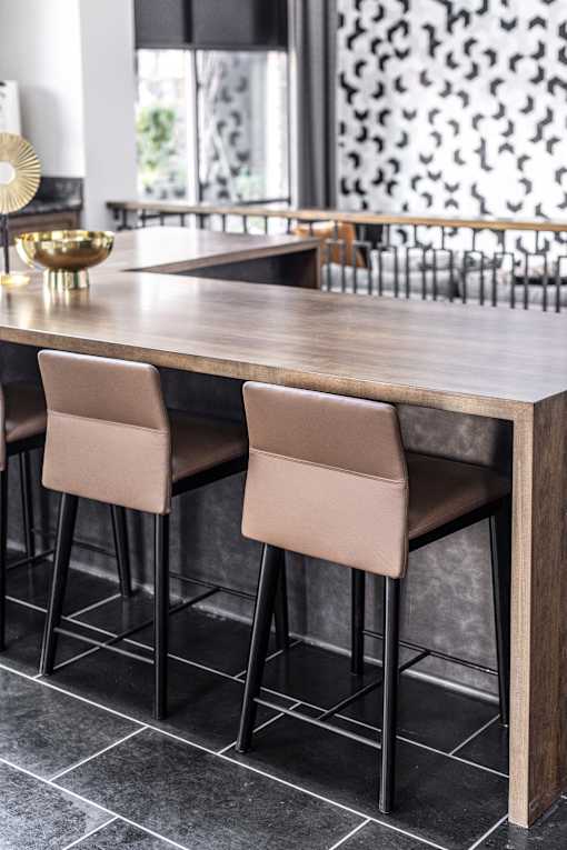 Two tan barstools are in front of a wooden bar.