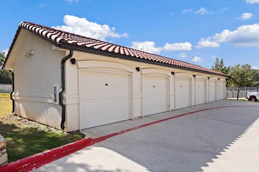 a row of garages with white doors and a red curb