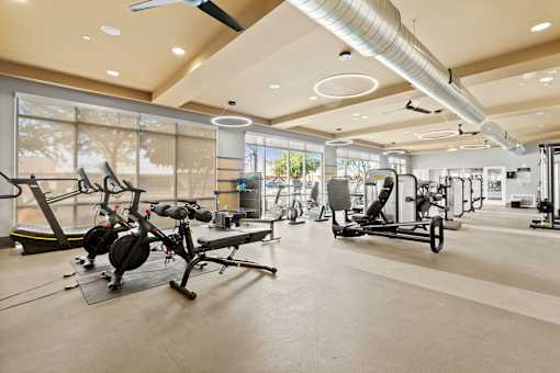 a gym with weights and other exercise equipment in a building with large windows