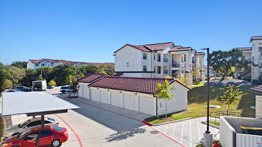 an aerial view of an apartment building with cars parked in a parking lot
