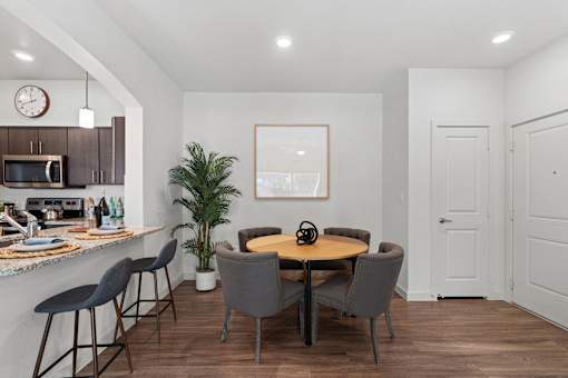 a dining room with a table and chairs and a kitchen with a counter and a