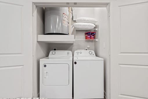 a small laundry room with a washer and dryer and a shelf above the