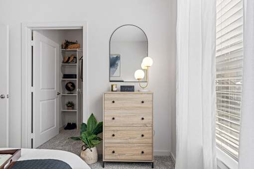a bedroom with a dresser with a mirror and a closet