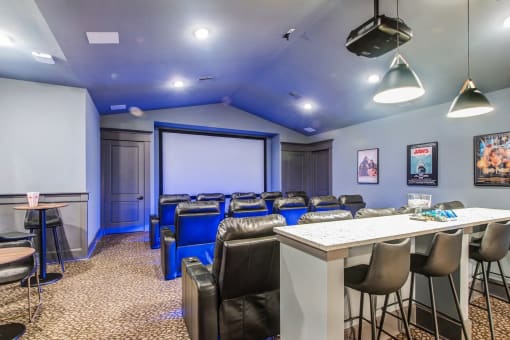 a room with a bar and chairs and a projector screen