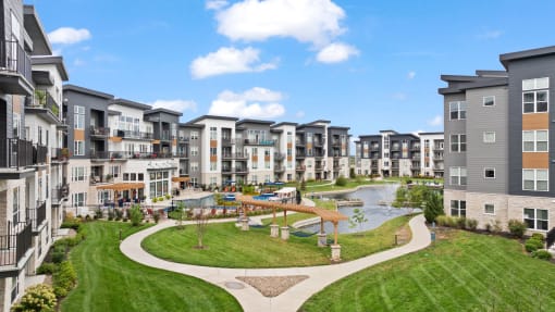 an aerial view of an apartment complex with a park and a pond