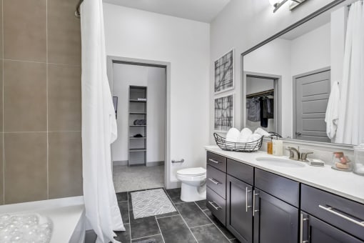 a bathroom with dark cabinets and a white shower curtain