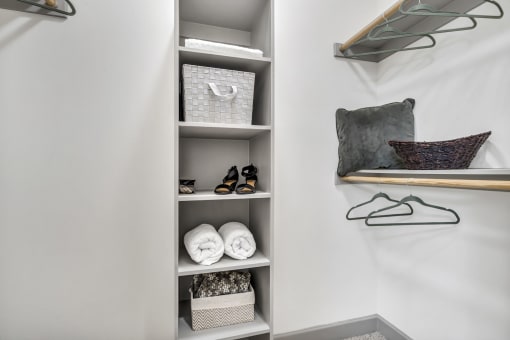 a shelving unit in a walk in closet with a shelf for towels and other items