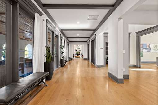 a long hallway with windows and wood floors and a bench