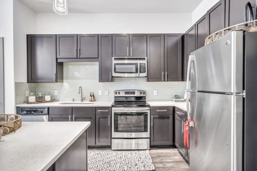 a kitchen with black cabinets and stainless steel appliances