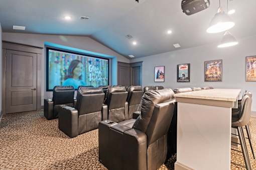a theater room with leather chairs and a table and a projection screen