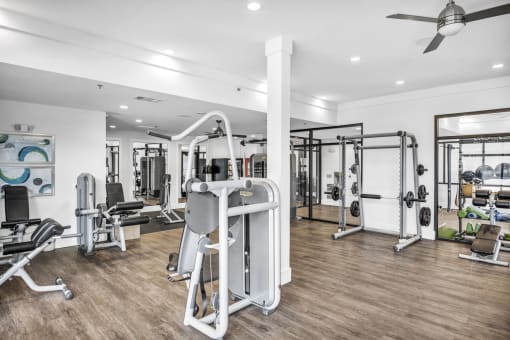 a gym with a lot of exercise equipment and a ceiling fan