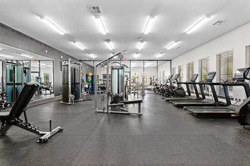 a gym with cardio equipment and glass walls
