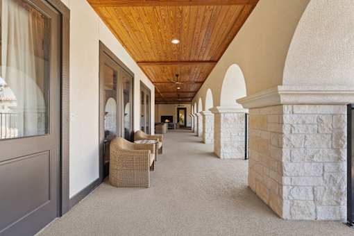 a long hallway with stone columns and chairs and a wood ceiling