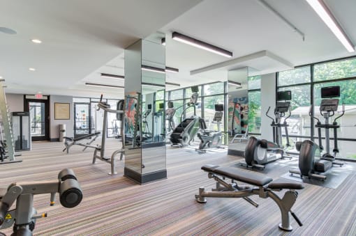 a gym with weights and cardio equipment in a building with large windows