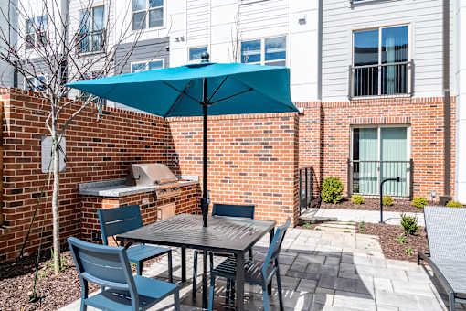 A patio with a table and chairs under a blue umbrella.