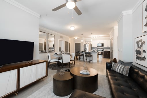 a living room and dining room with white walls and a ceiling fan