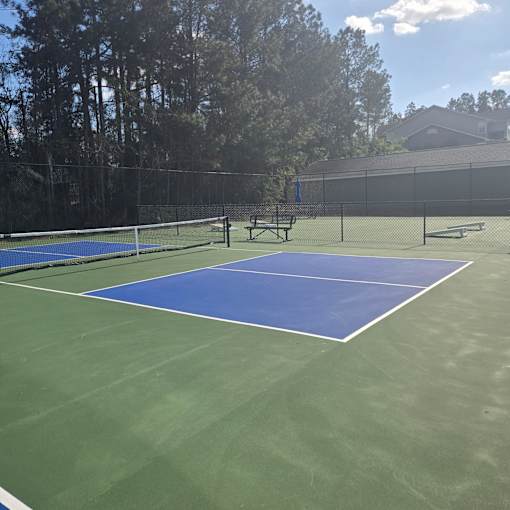 A tennis court with a net and two benches.