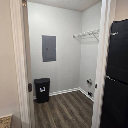 A small room with a black fridge and a black bin.
