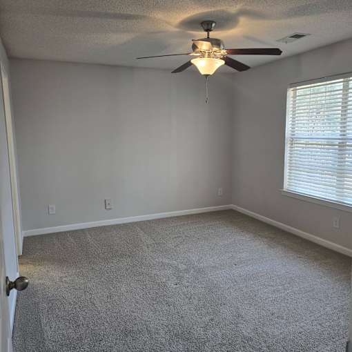 A room with a ceiling fan and carpeted floor.