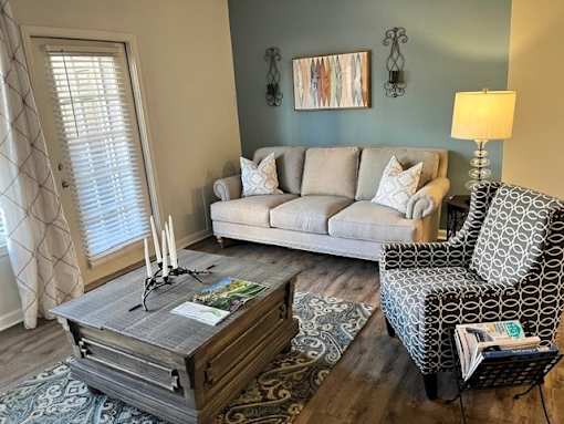 A living room with a grey couch, a patterned chair, and a coffee table.