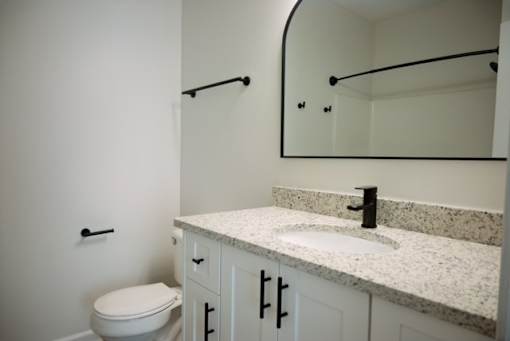 A bathroom with a toilet, sink, and mirror.