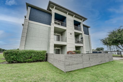 an apartment building with a wooden fence in front of it  at Highland Luxury Living, Lewisville, TX, 75067