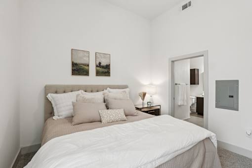 A bedroom with a large bed and two pictures on the wall at Everra Midtown Park Apartments, Dallas, TX, 75231