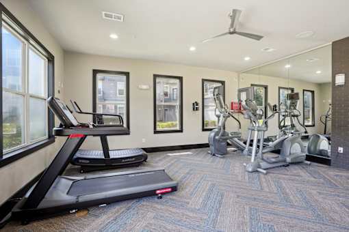 A treadmill is in the foreground of a well-equipped gym at Highline Urban Lofts Apartments, Cypress, Texas