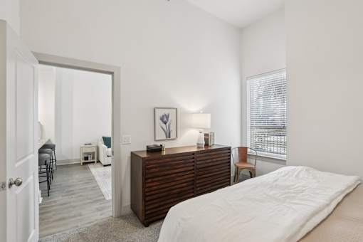 A bedroom with a bed, dresser, and chair at Everra Midtown Park Apartments, TX, 75231