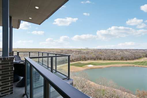 A balcony overlooks a golf course with a lake.