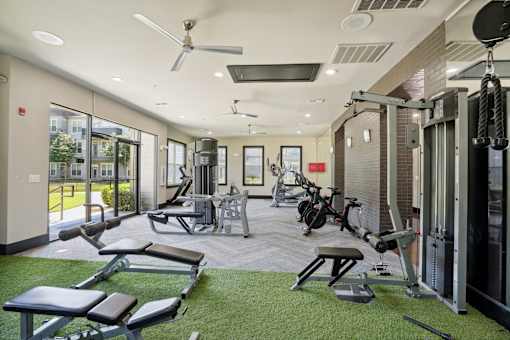 A gym with a variety of equipment including weights, a bench press, and a treadmill at Highline Urban Lofts Apartments, Cypress