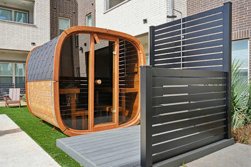 A wooden pod sits on a grey platform in front of a black gate.