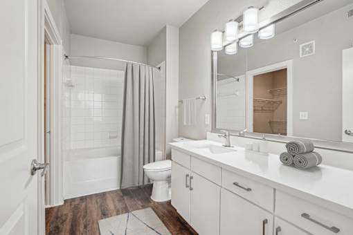 A white bathroom with a toilet, sink, and shower at Highline Urban Lofts Apartments, Cypress, TX, 77429