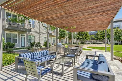 A wooden patio with blue cushions and chairs at Highline Urban Lofts Apartments, Texas