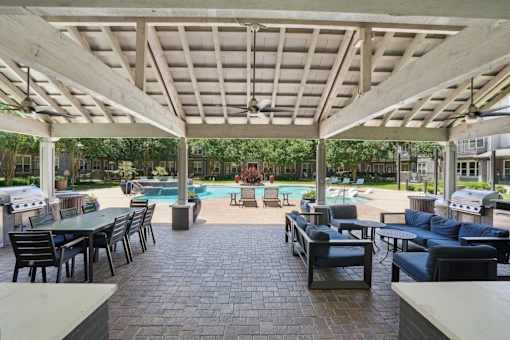 A patio with a pool and furniture under a roof at Highline Urban Lofts Apartments, Cypress 77429