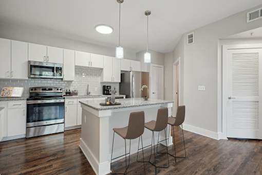 A modern kitchen with a white island and brown chairs at Highline Urban Lofts Apartments, Cypress, TX, 77429