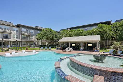 A swimming pool with a fountain in the middle of it at Highline Urban Lofts Apartments, Cypress, TX