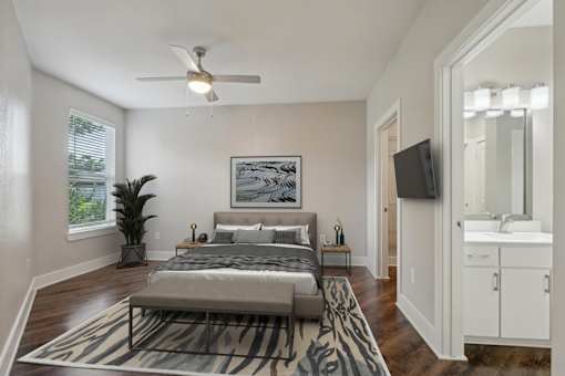 A bedroom with a bed, a rug, a plant, and a television at Highline Urban Lofts Apartments, Cypress