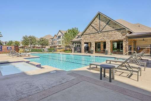 pool with stone building in the background at Vine + Vail Townhomes and Apartments, Grapevine Texas