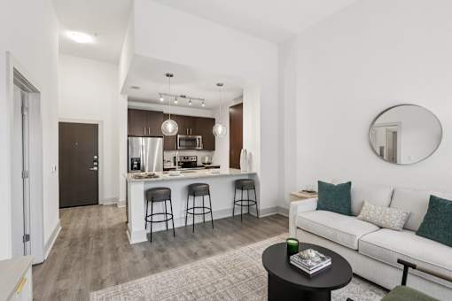 A modern living room with a kitchen area in the background at Everra Midtown Park Apartments, Dallas, TX, 75231